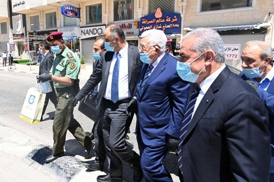 رئيس عربي يسير في الشارع مرتدياً الكمامة والقفازات الطبية